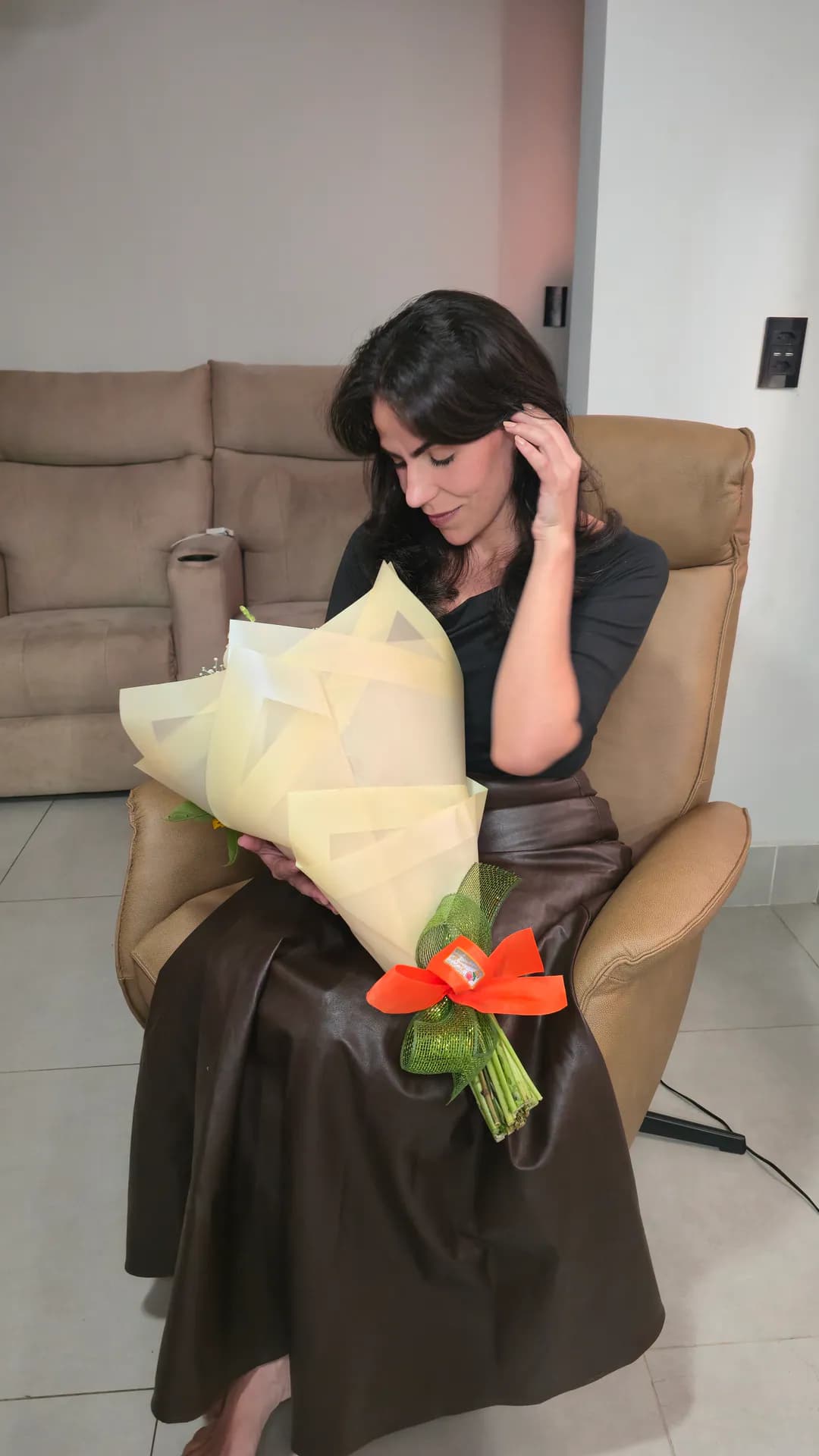 Cecília sentada na Poltrona Levita Damie segurando um buquê de flores.