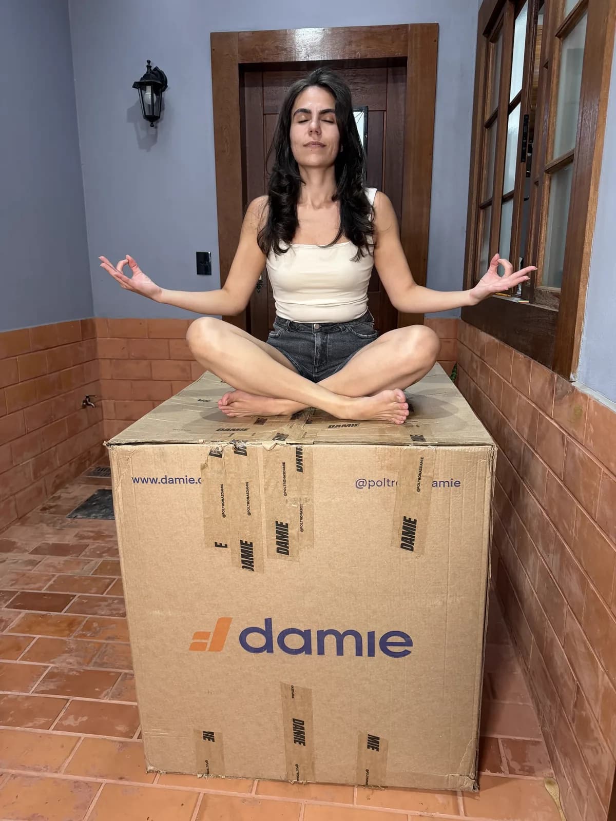 Cecília meditando sobre uma caixa de entrega da Damie